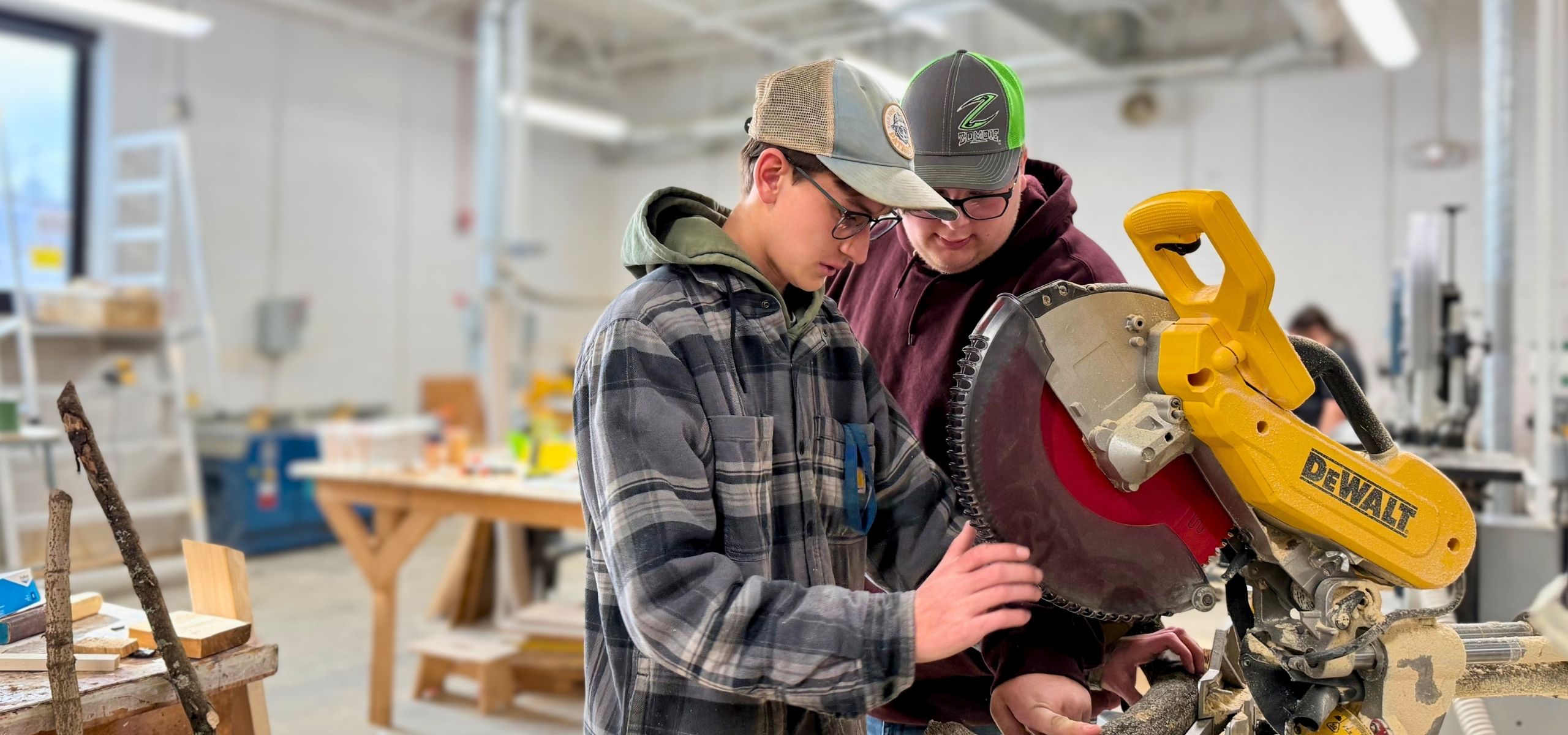 Two young people learning to use a miter saw in a Ready4Real training shop