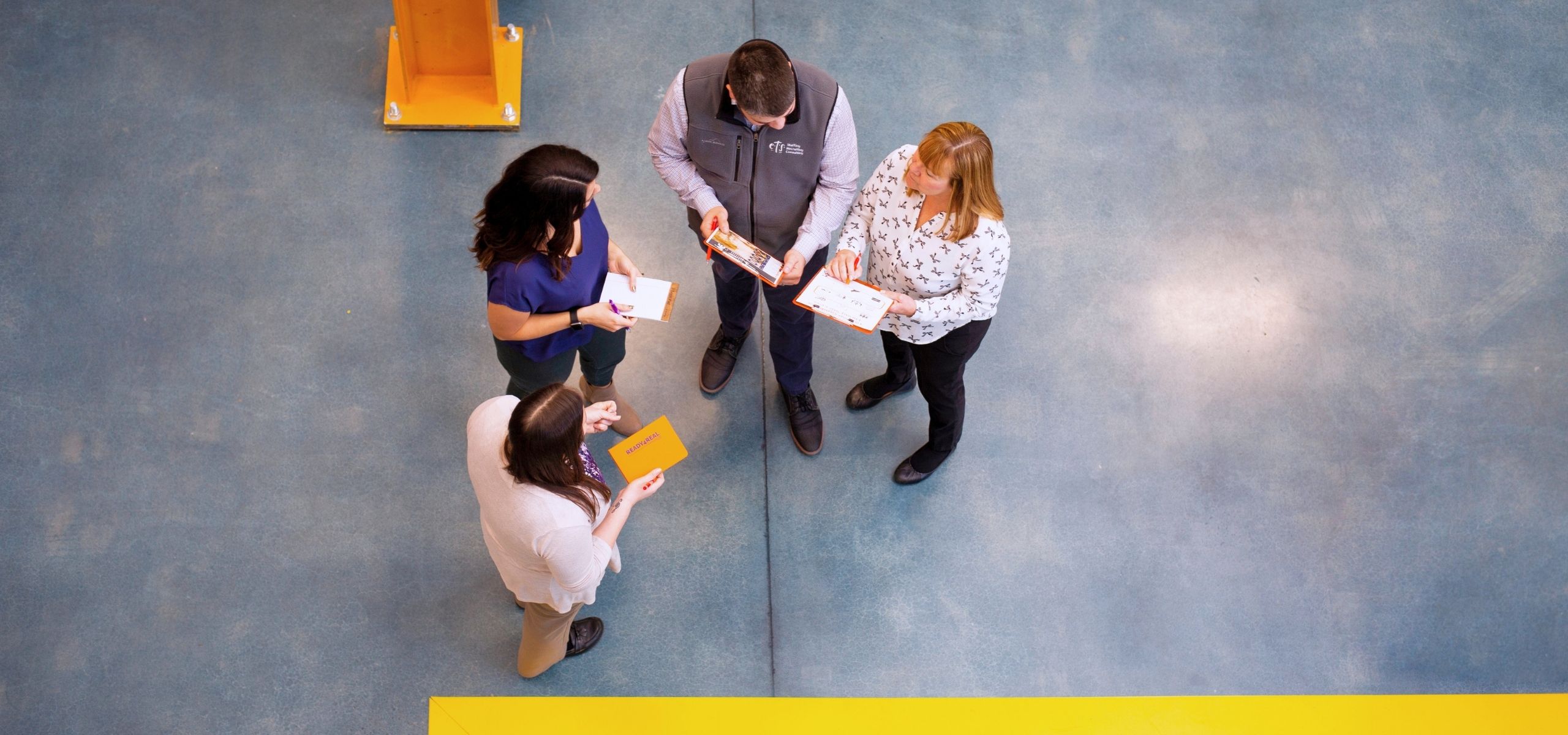 ETS team huddle on a warehouse floor, overhead view