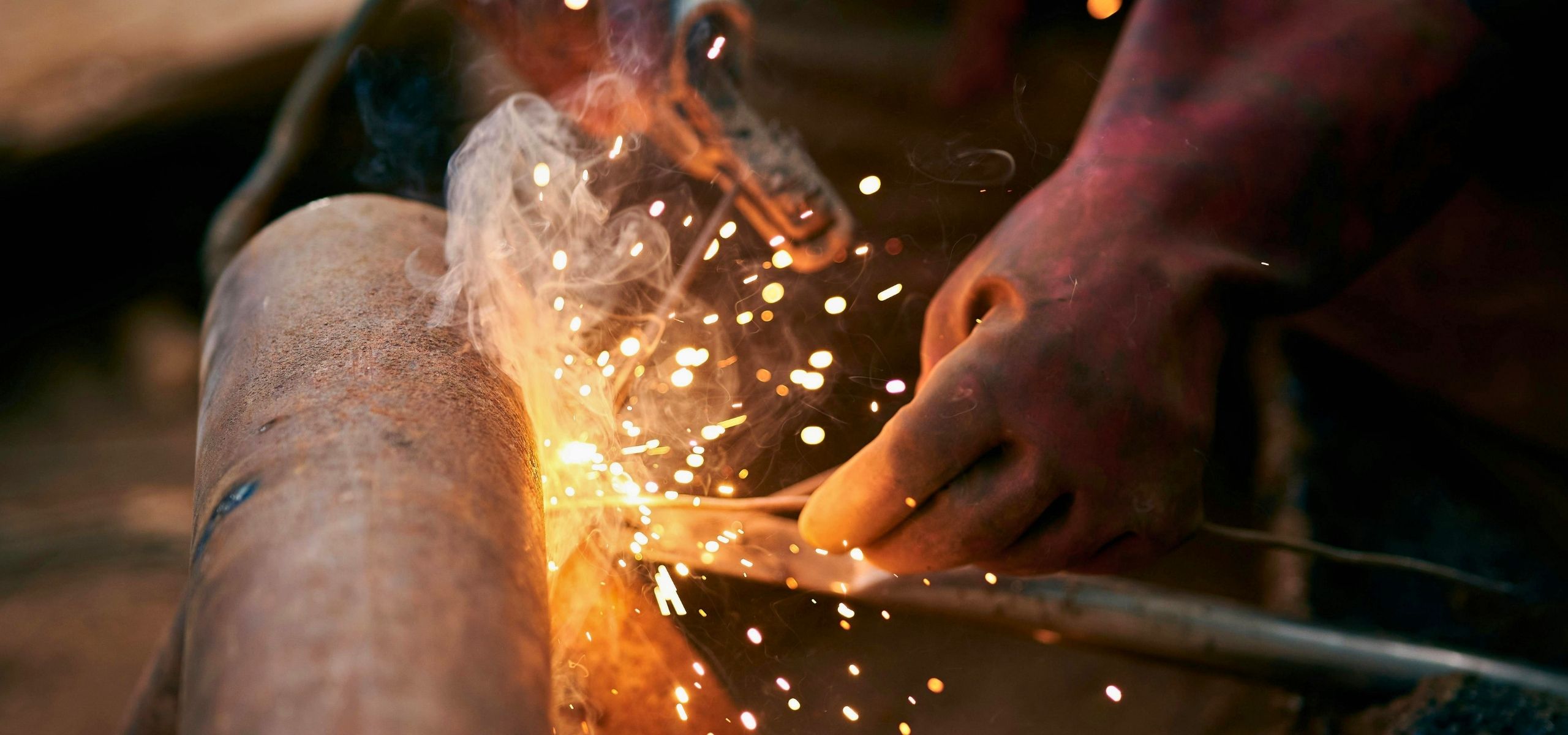Welder joining metal with sparks flying during a fabrication job